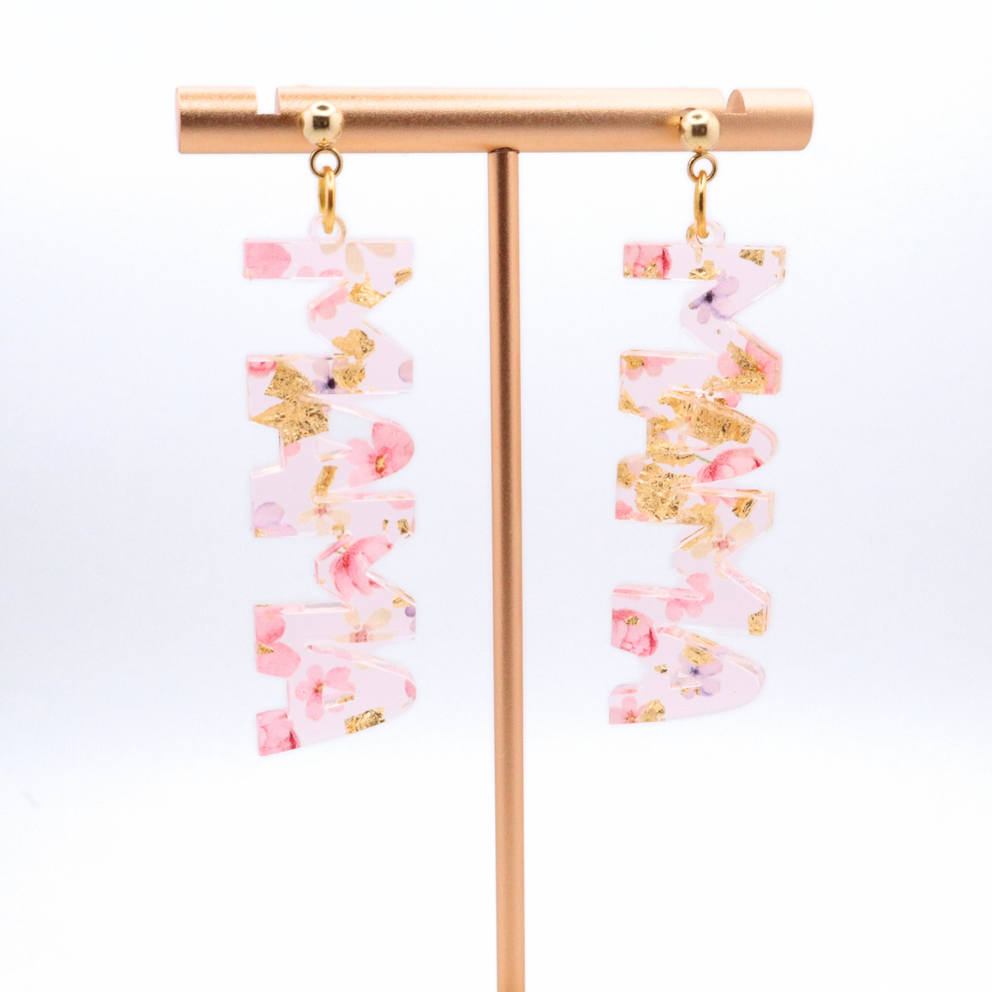 Pair of mama earrings with pink and gold accents on a white background