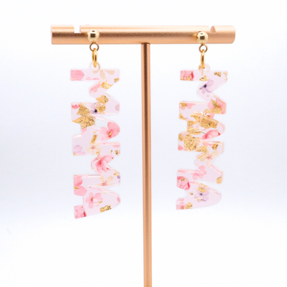 Pair of mama earrings with pink and gold accents on a white background