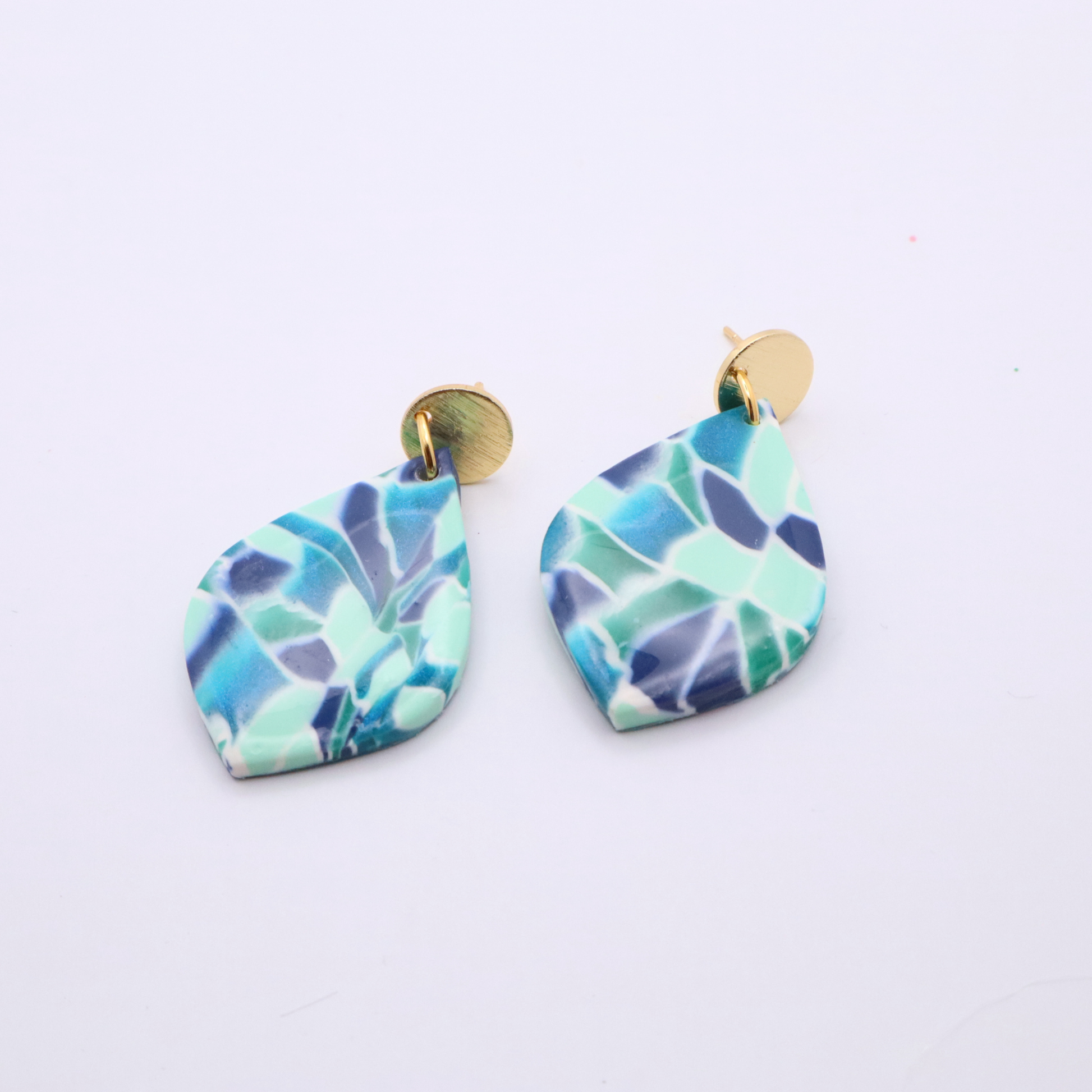 Close-up of mosaic patterned teardrop earrings in turquoise, navy, and mint with 18k gold plated studs on white background