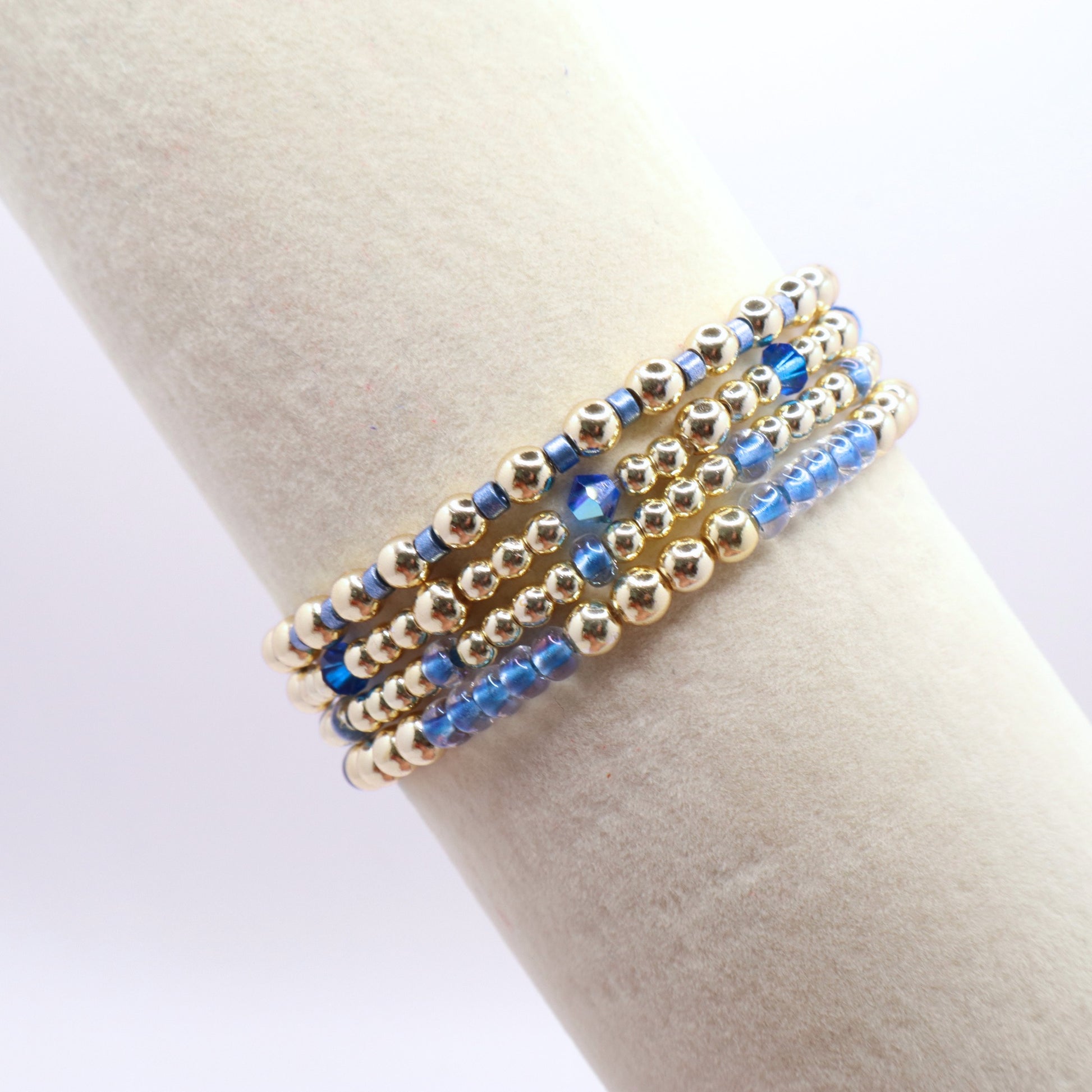 Four-piece periwinkle blue and gold hematite bracelet stack with crystal accents.