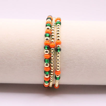 Three orange, green, and gold beaded bracelets on a display