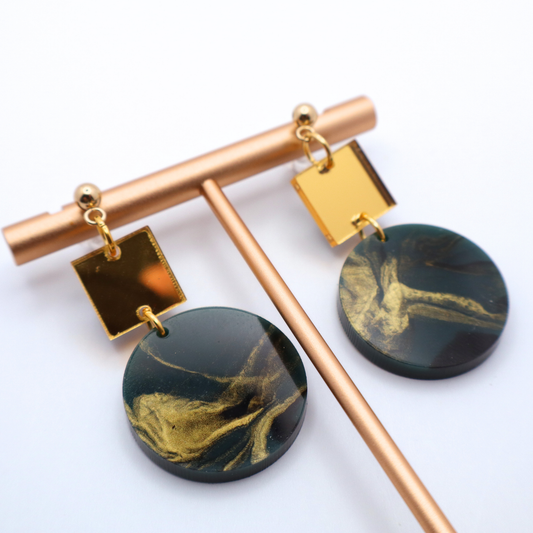 Pair of earrings with gold and green marbled design on a white background