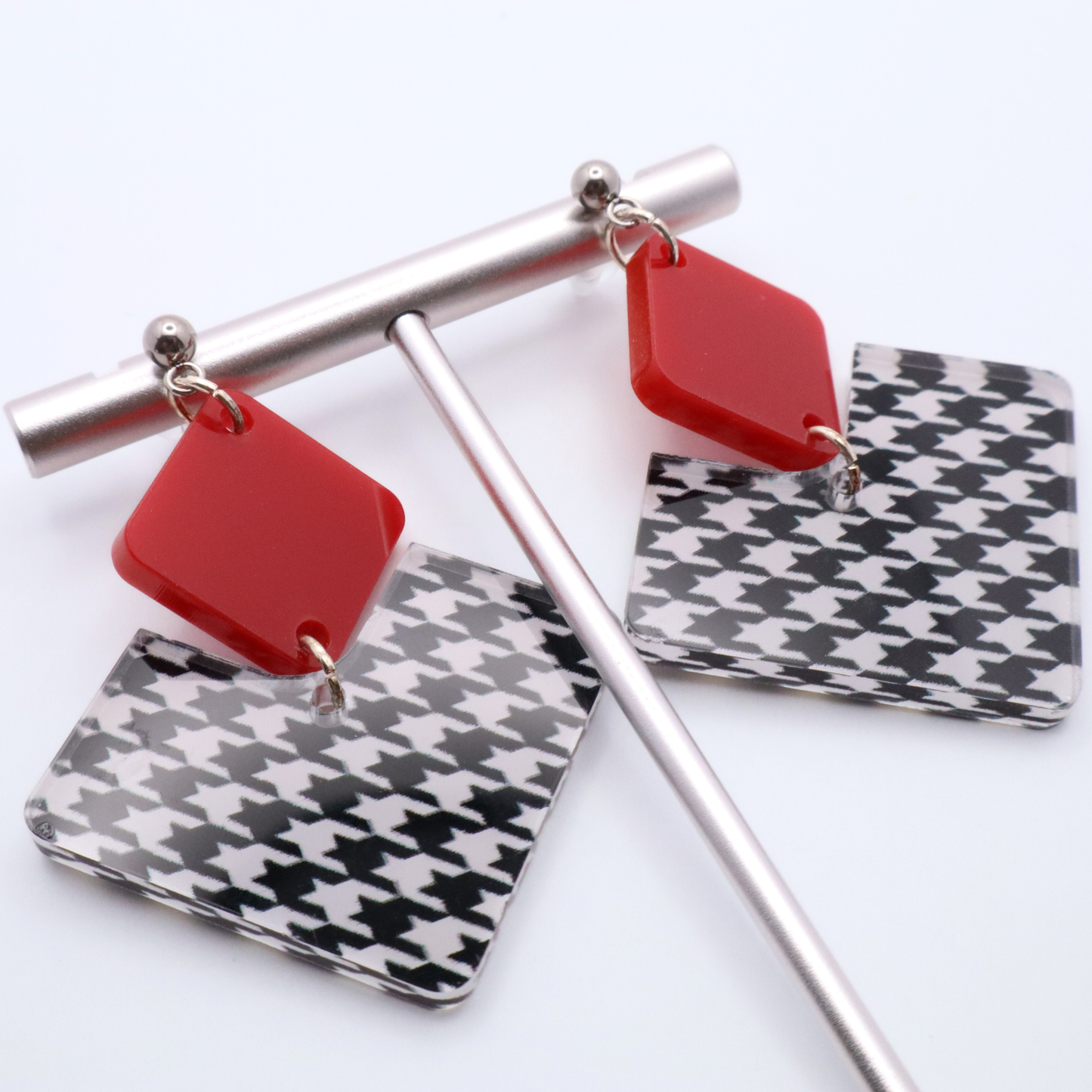 Earrings with red and houndstooth patterned components on a white background