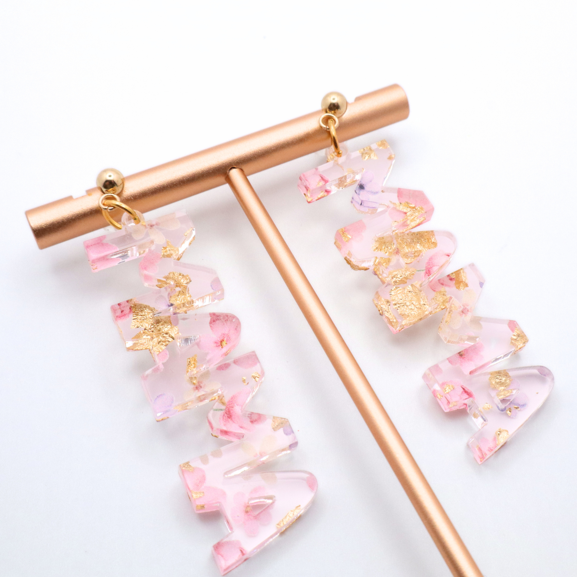 Pink and gold mama earrings on a white background