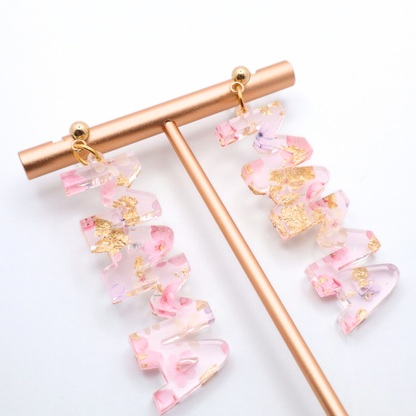 Pink and gold mama earrings on a white background