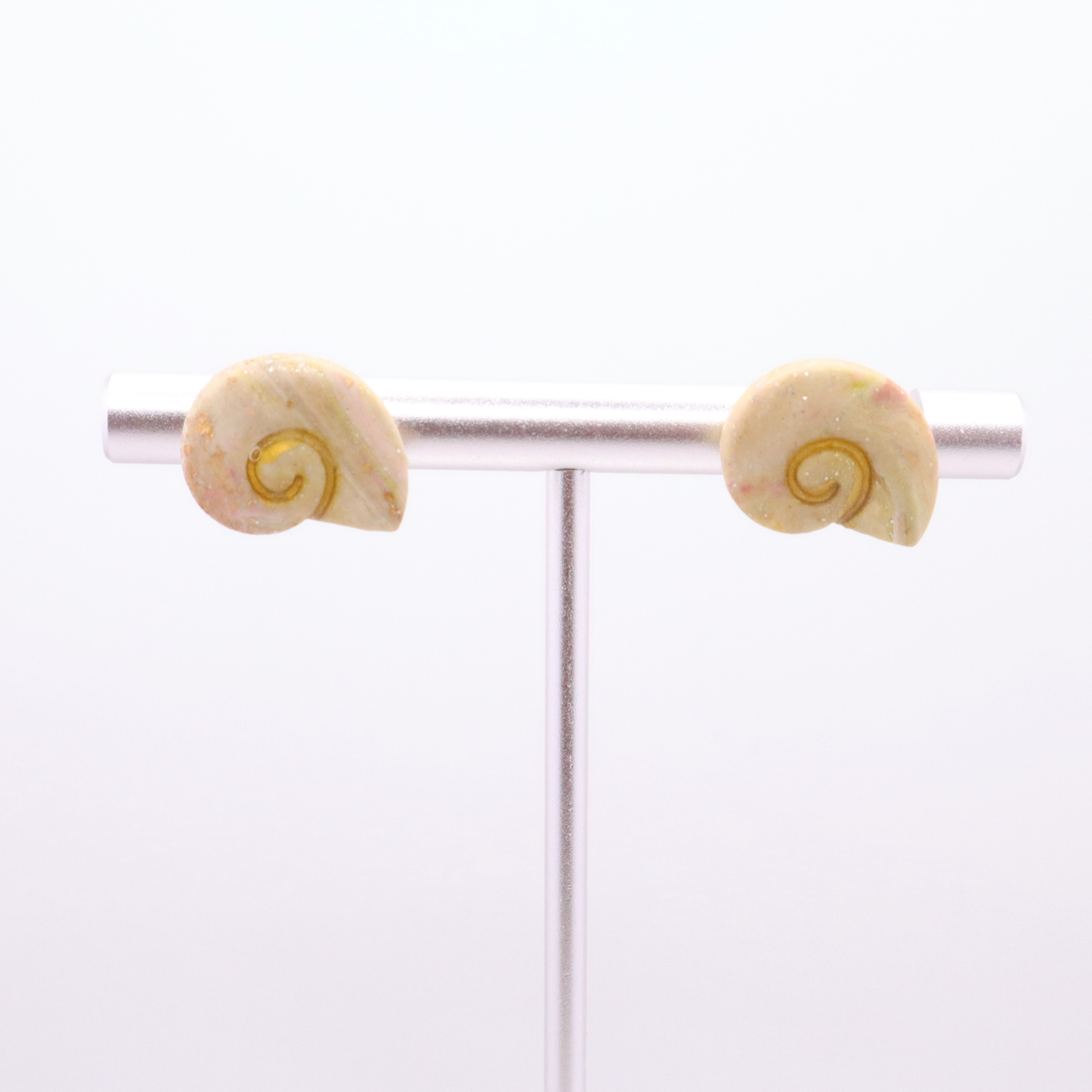 Lightweight resin shell studs in ivory, blush, and gold tones on jewelry bar display