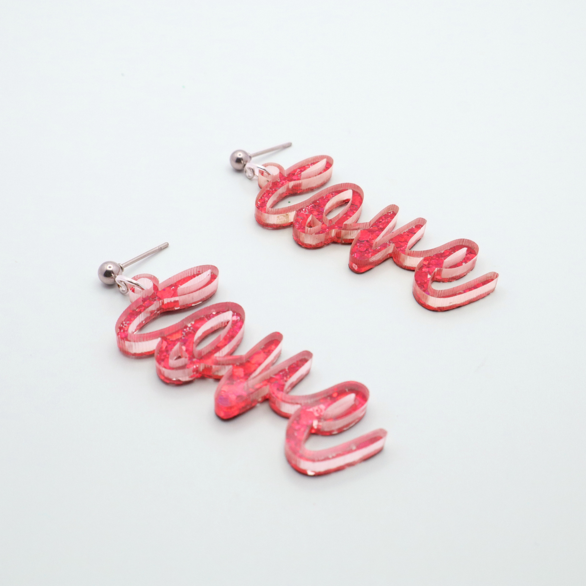 Pink 'love' earrings on a light gray background