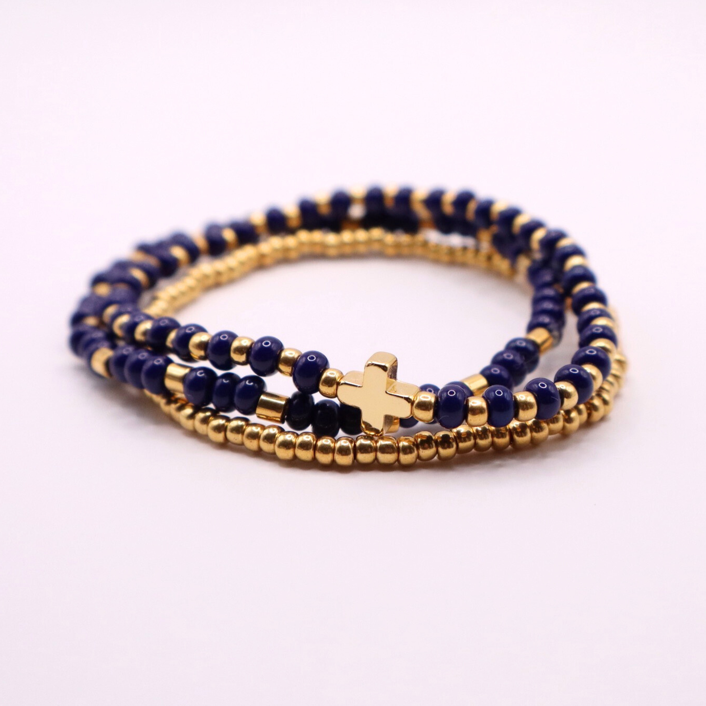 Three beaded bracelets with gold plated and navy beads on a white background