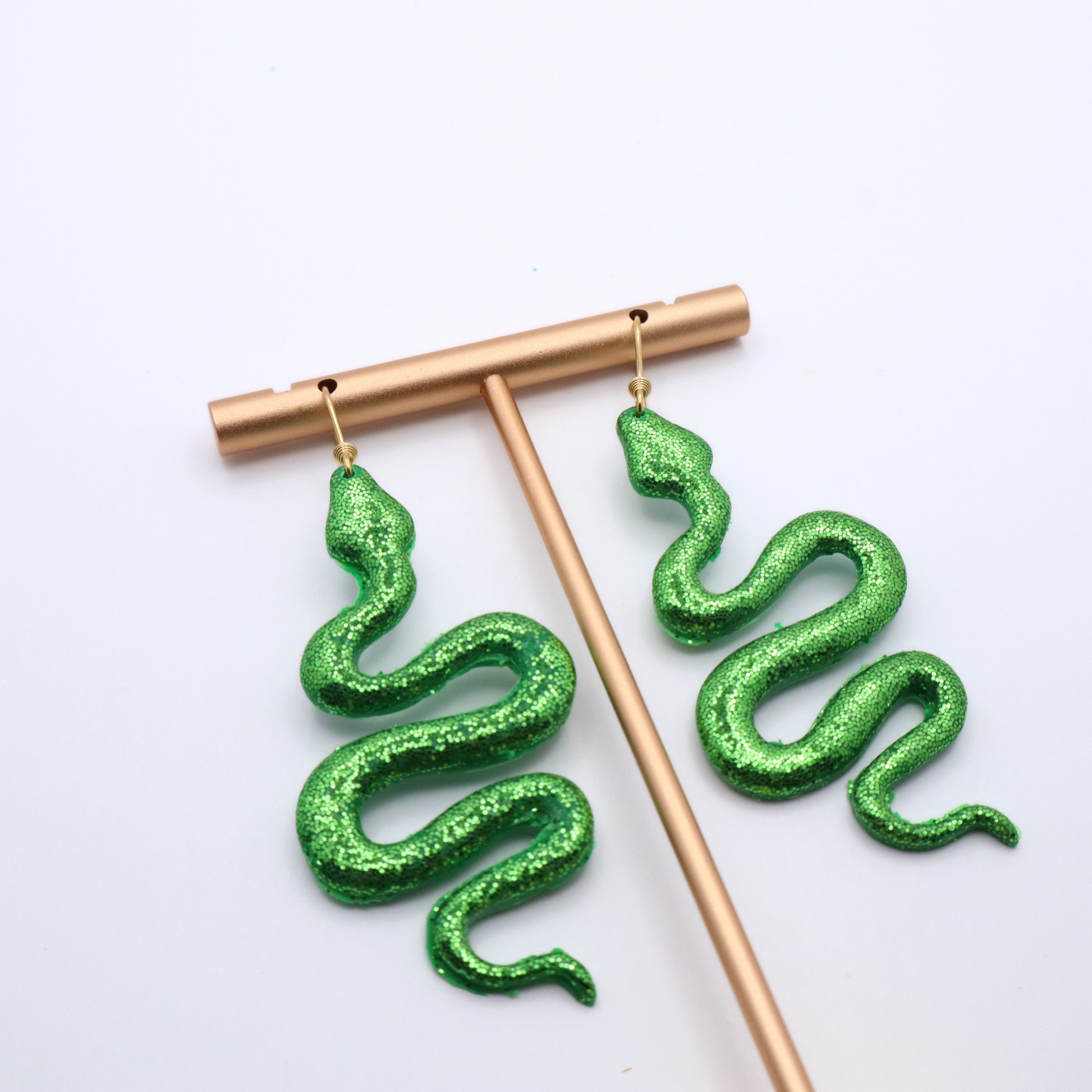 Green glitter snake-shaped earrings on a white background