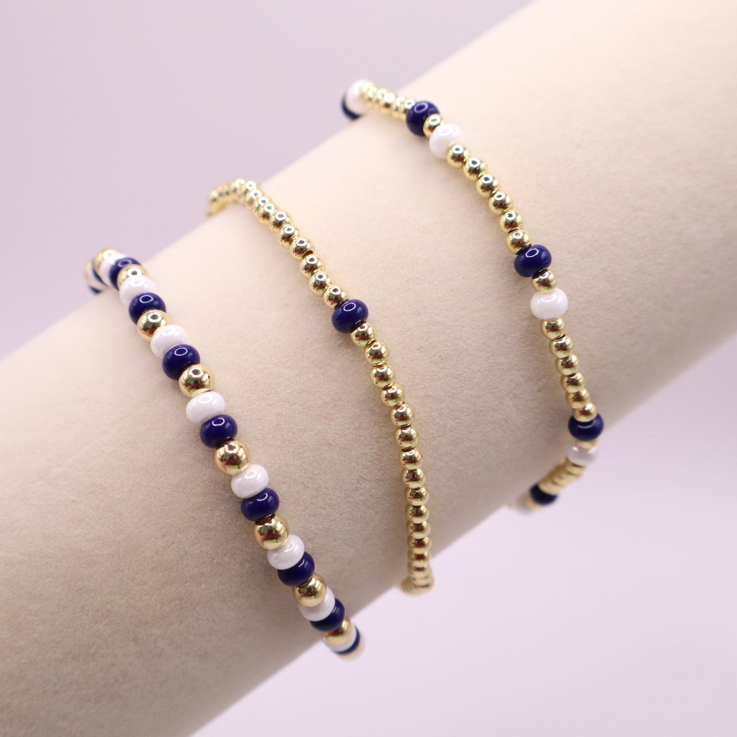 Three beaded bracelets on a wrist against a light background