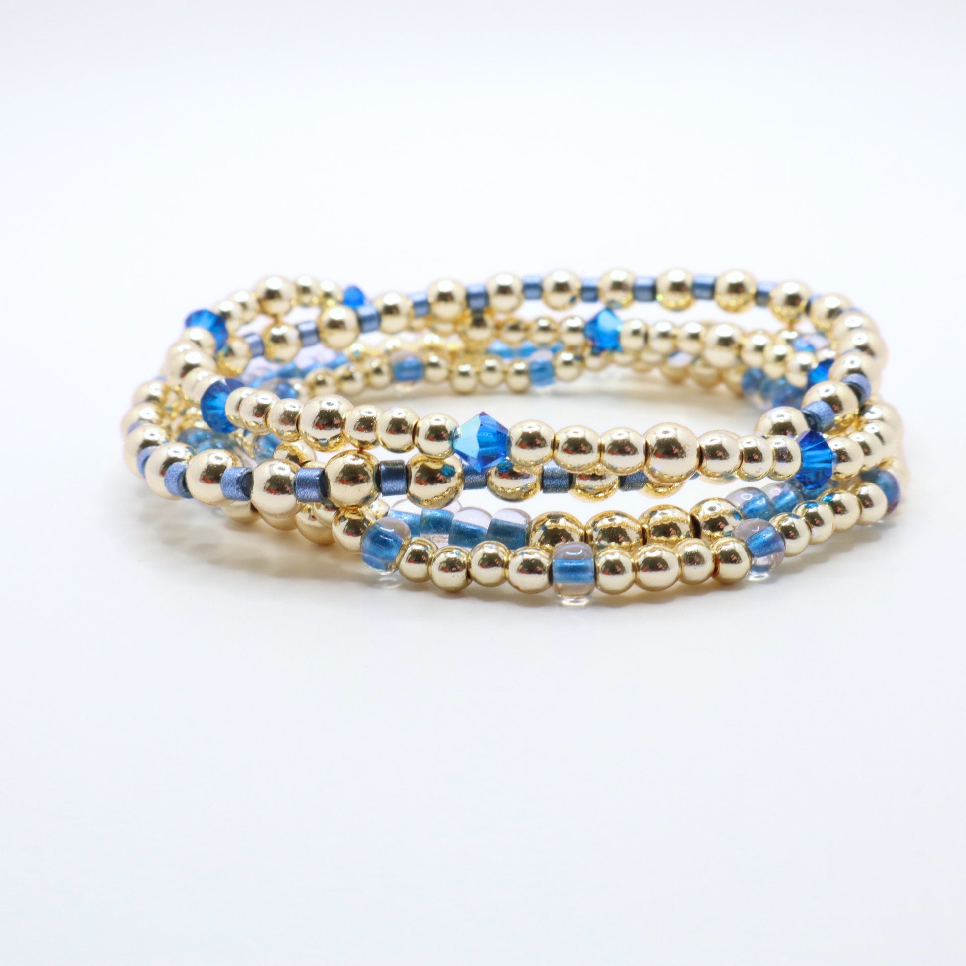 Elegant stackable bracelet collection with periwinkle beads and gold accents.