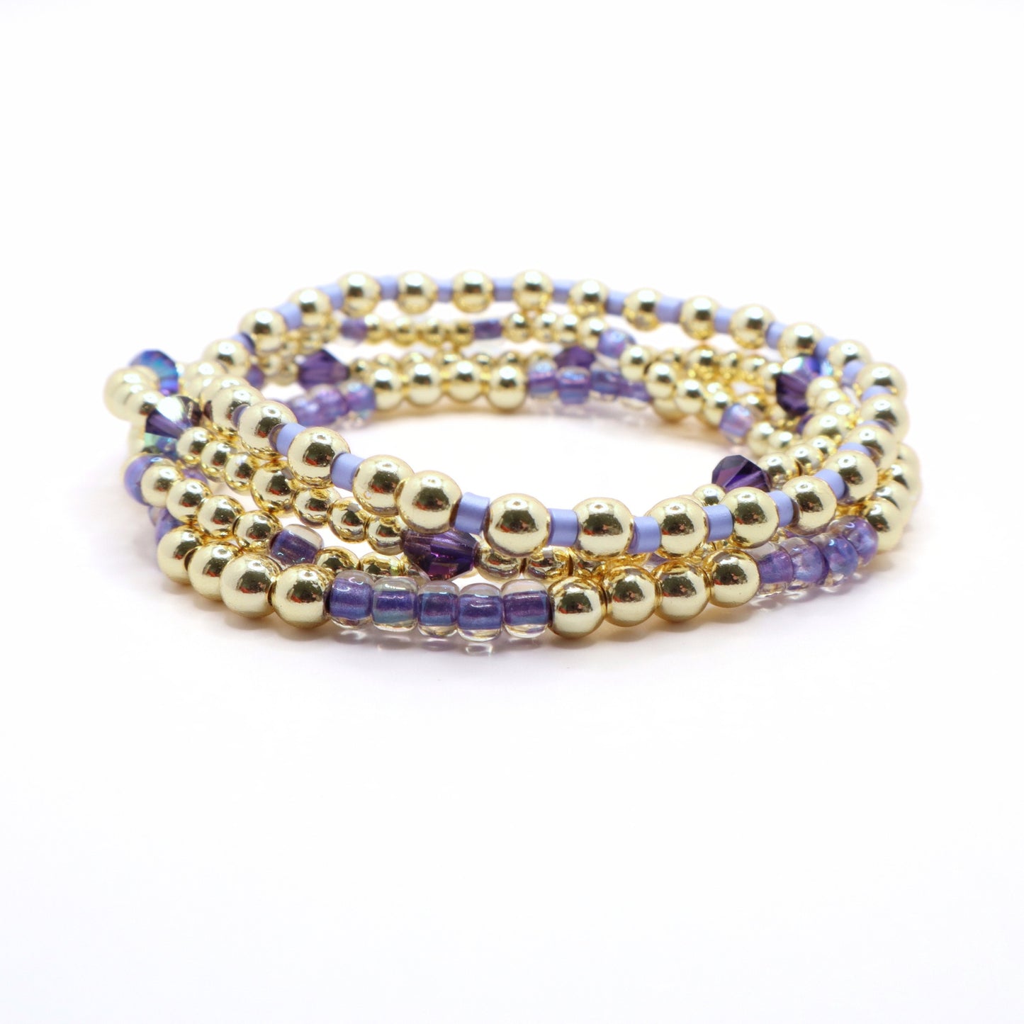 Elegant lavender bracelet stack with gold beads displayed on a wrist jewelry stand.