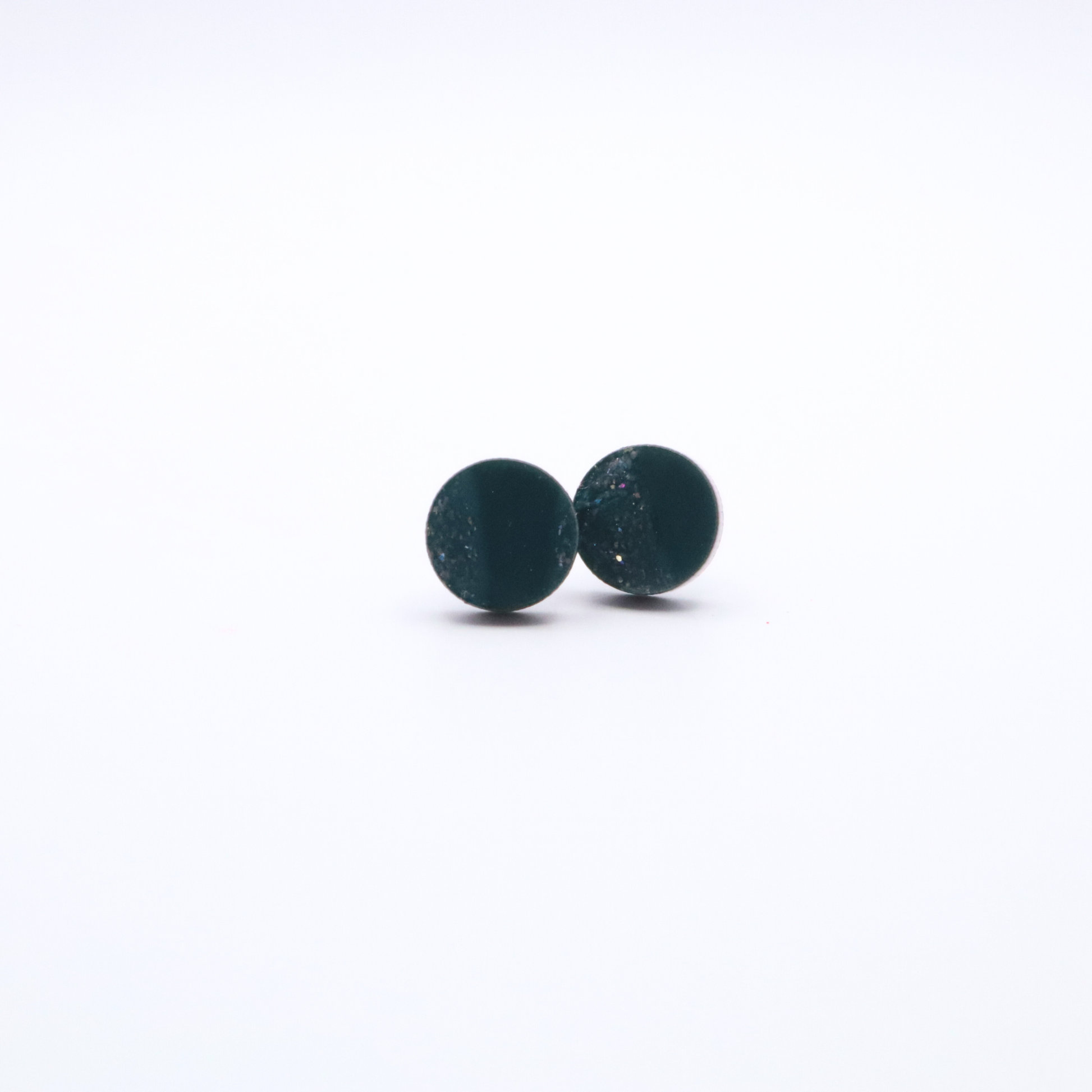 Pair of teal green round stud earrings on a white background