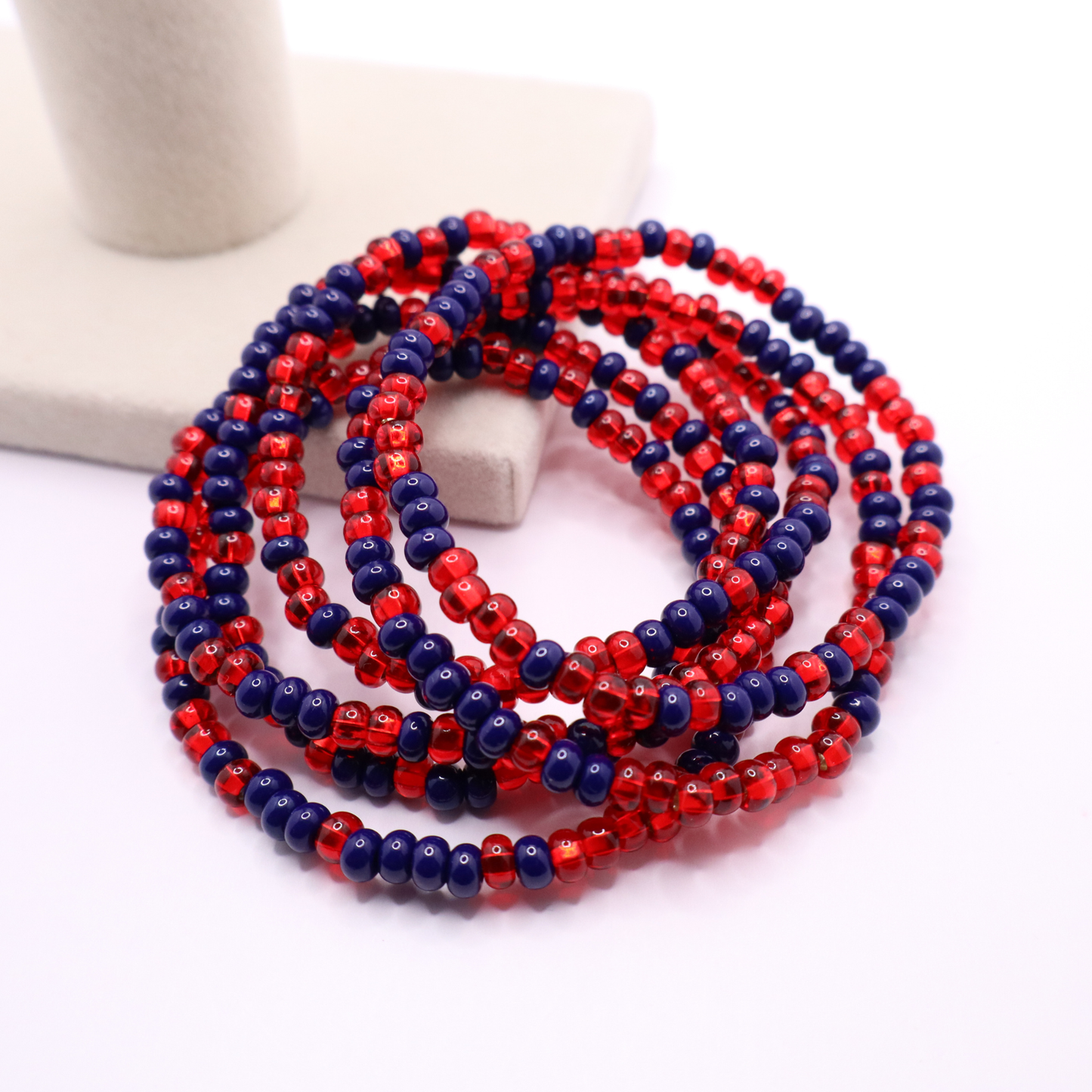 Set of six navy blue and red seed bead stretch bracelets featuring random navy blue and red seed beads on a white background