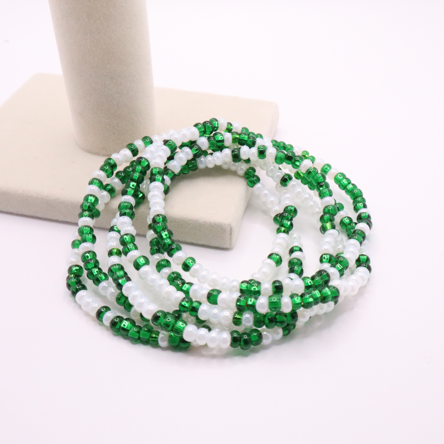 Set of six green and white seed bead stretch bracelets featuring random green and white seed beads on a white background