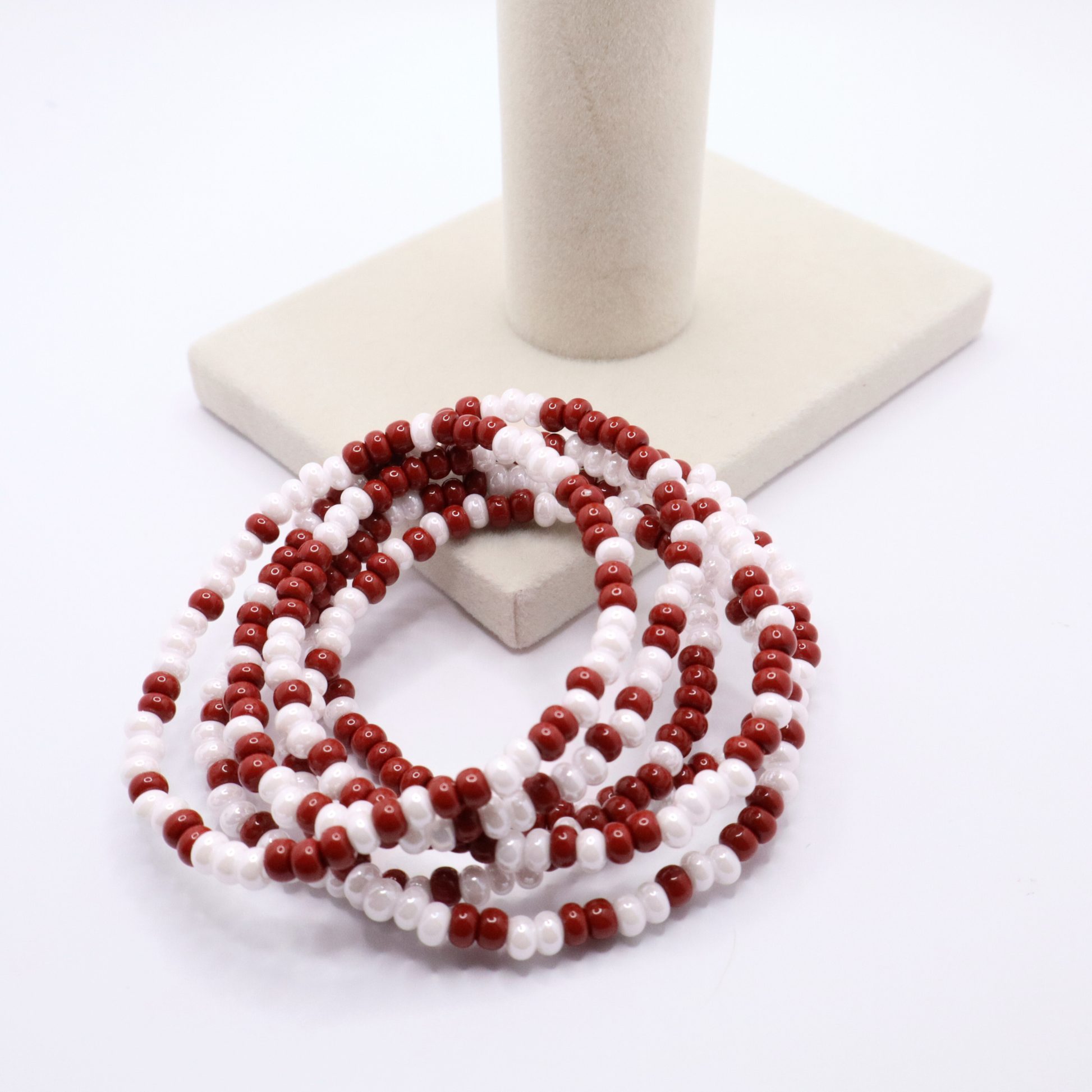 Set of six crimson and white seed bead stretch bracelets featuring random crimson and white seed beads on a white background