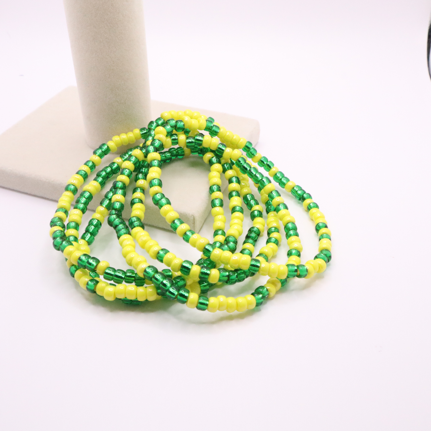 Set of six green and yellow seed bead stretch bracelets featuring random green and yellow seed beads on a white background