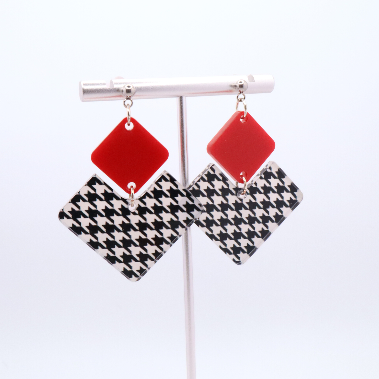 Pair of earrings with red and houndstooth pattern on a white background