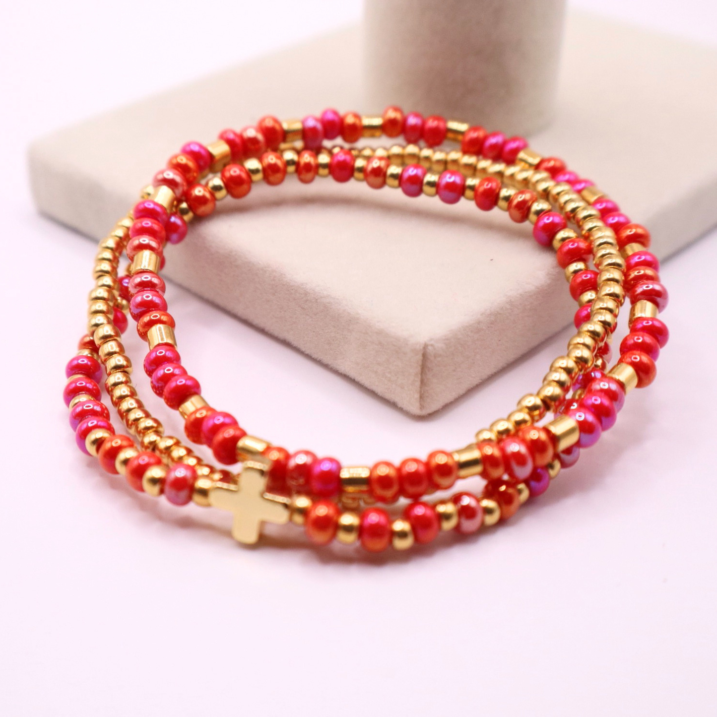 Stack of pink and gold beaded bracelets on a white background
