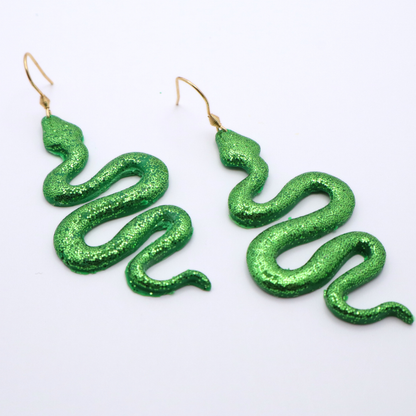 Green glitter snake-shaped earrings on a white background