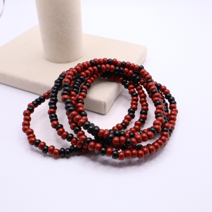 Set of six maroon and black seed bead stretch bracelets featuring random maroon and black seed beads on a white background