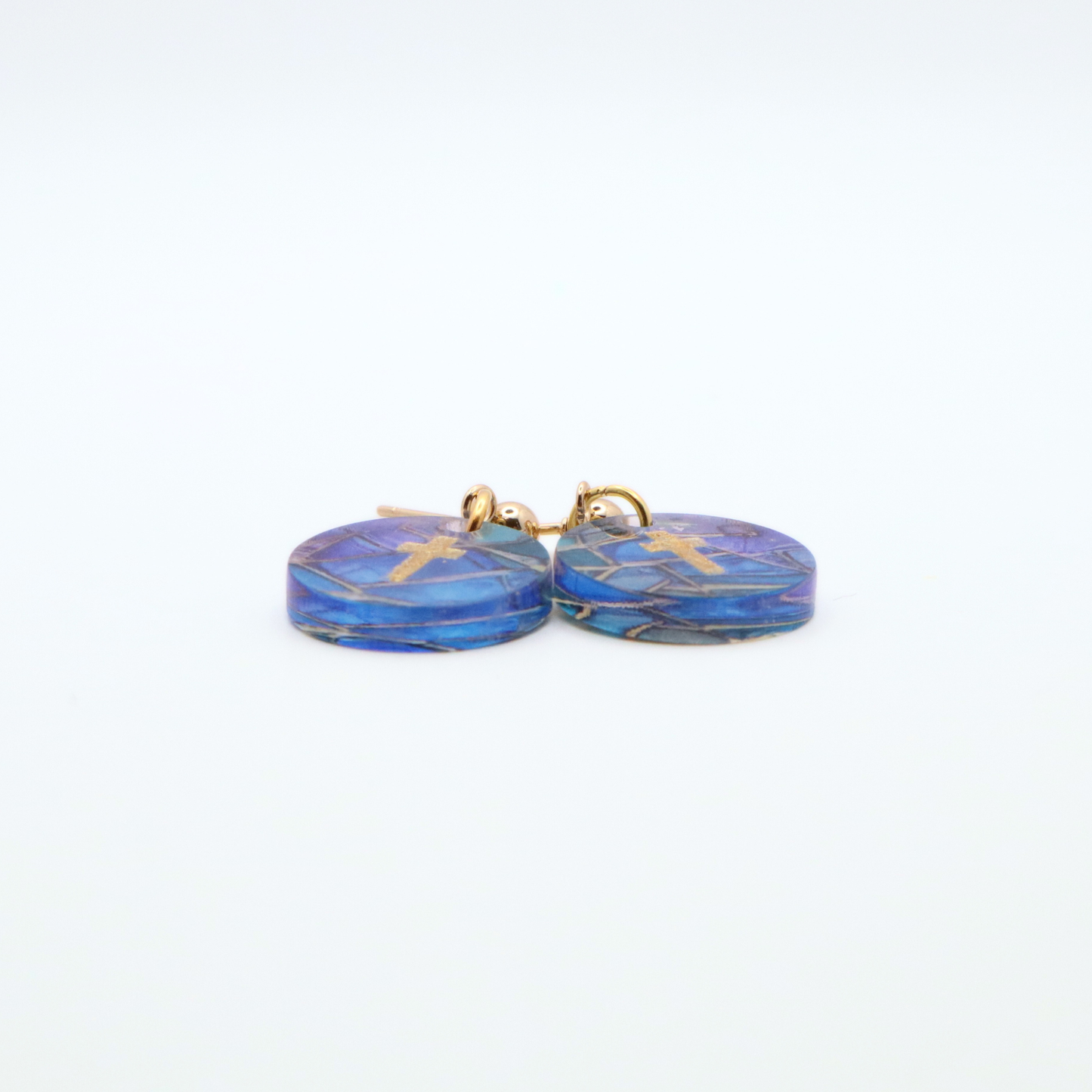 Side view of acrylic cross earrings showing thickness and glossy finish with blue stained glass pattern and gold cross detail on stainless steel posts