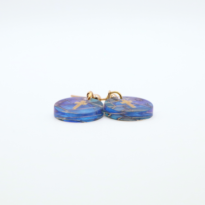 Side view of acrylic cross earrings showing thickness and glossy finish with blue stained glass pattern and gold cross detail on stainless steel posts