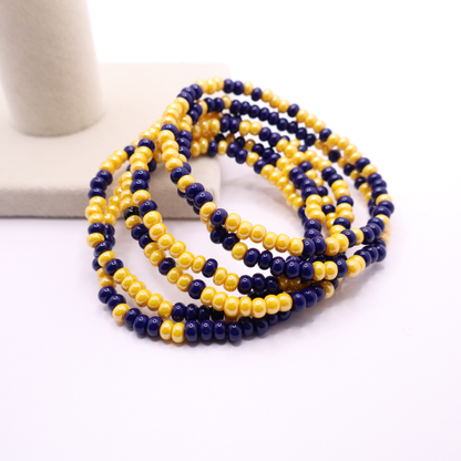 Set of six navy blue and gold seed bead stretch bracelets featuring random red and white seed beads on a white background