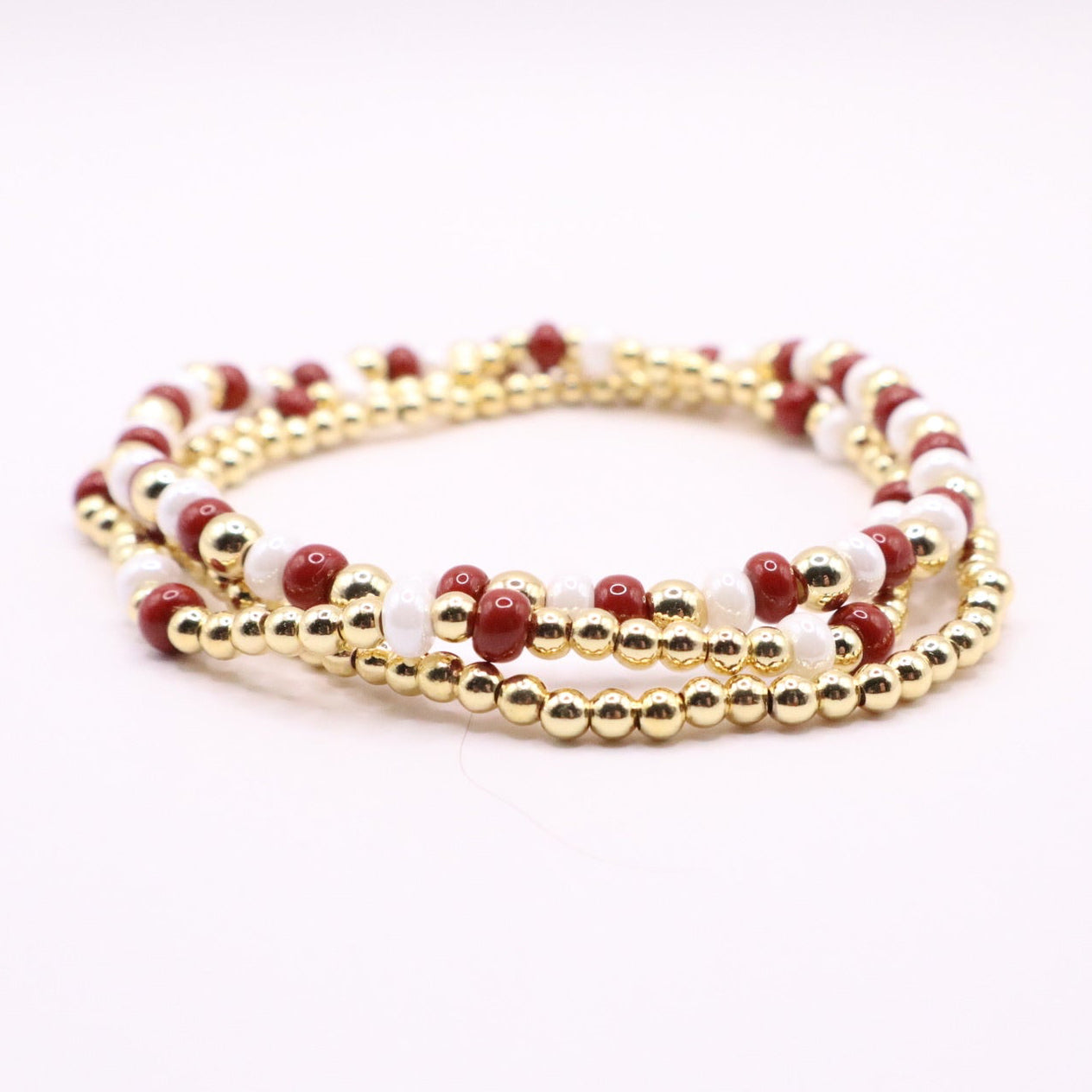 Crimson gold and white bracelets on a white background
