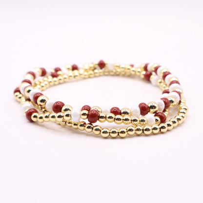 Crimson gold and white bracelets on a white background
