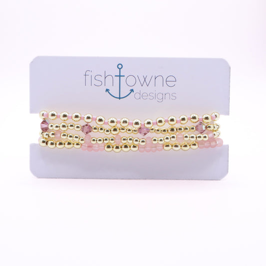 Four-piece blush pink and gold hematite bracelet stack with crystal accents.