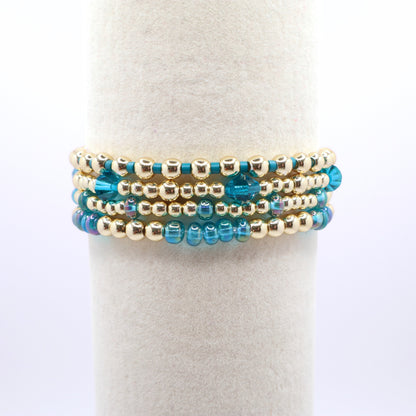 Three coordinating blue and gold stretch bracelets for stacking.