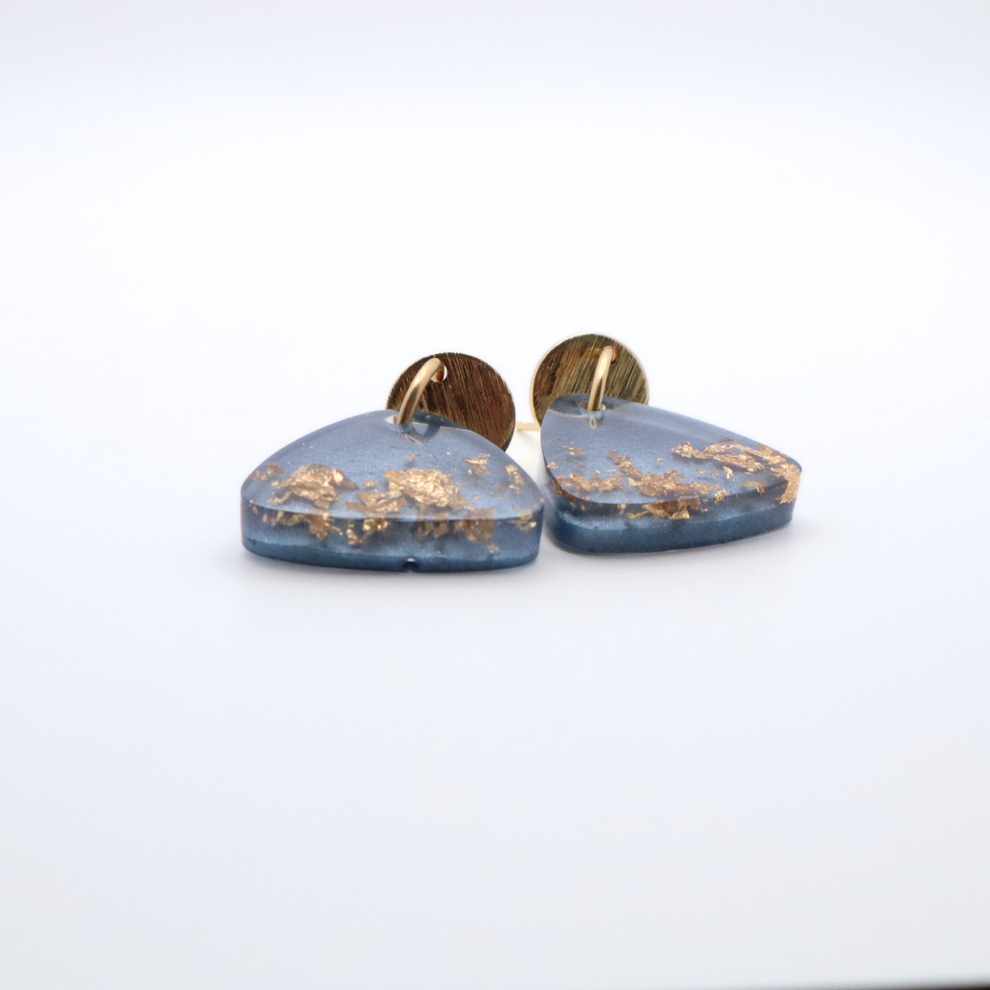 Blue resin earrings with gold flakes on a white background