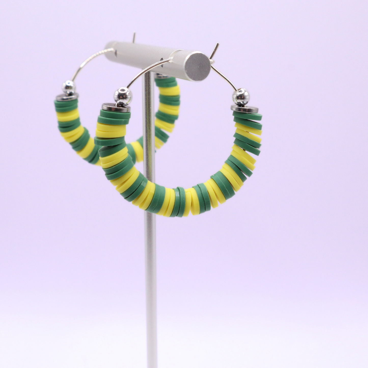 Handmade green and yellow polymer clay heishi bead hoop earrings with silver spacers shown on a white background with display card