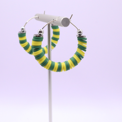 Handmade green and yellow polymer clay heishi bead hoop earrings with silver spacers shown on a white background with display card