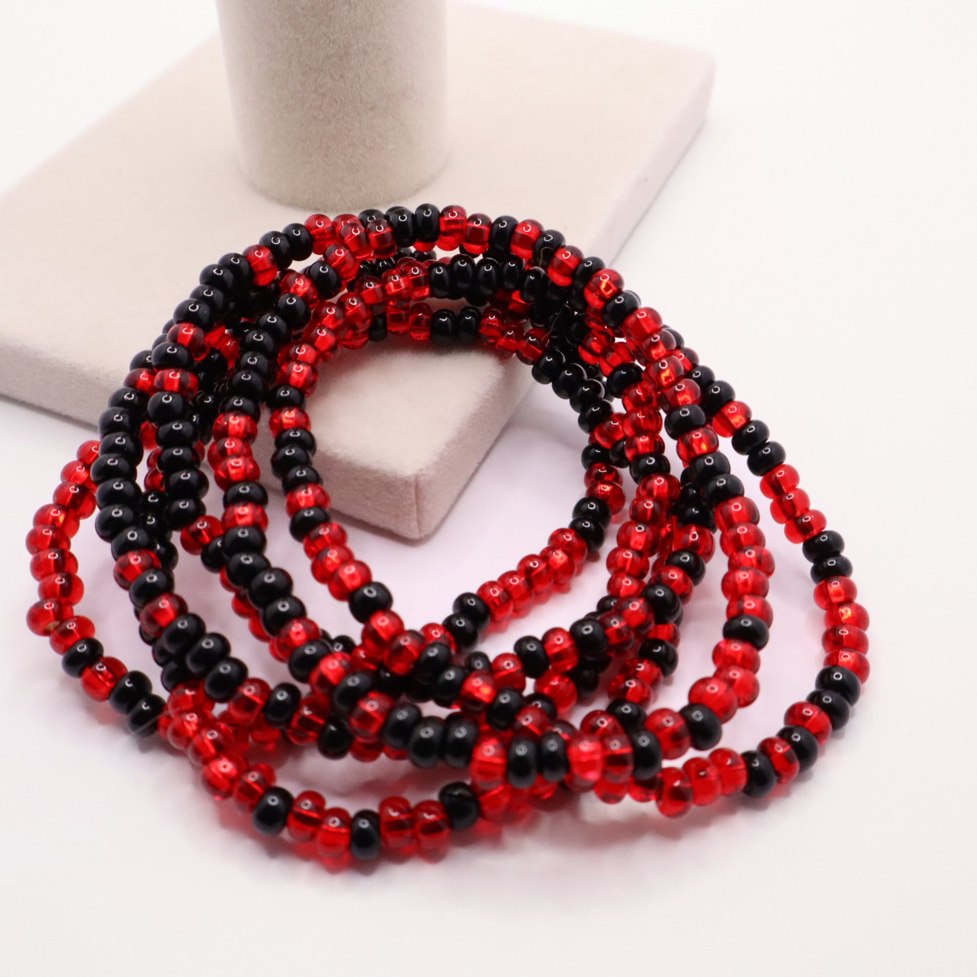 Set of six red and black seed bead stretch bracelets featuring random red and black seed beads on a white background