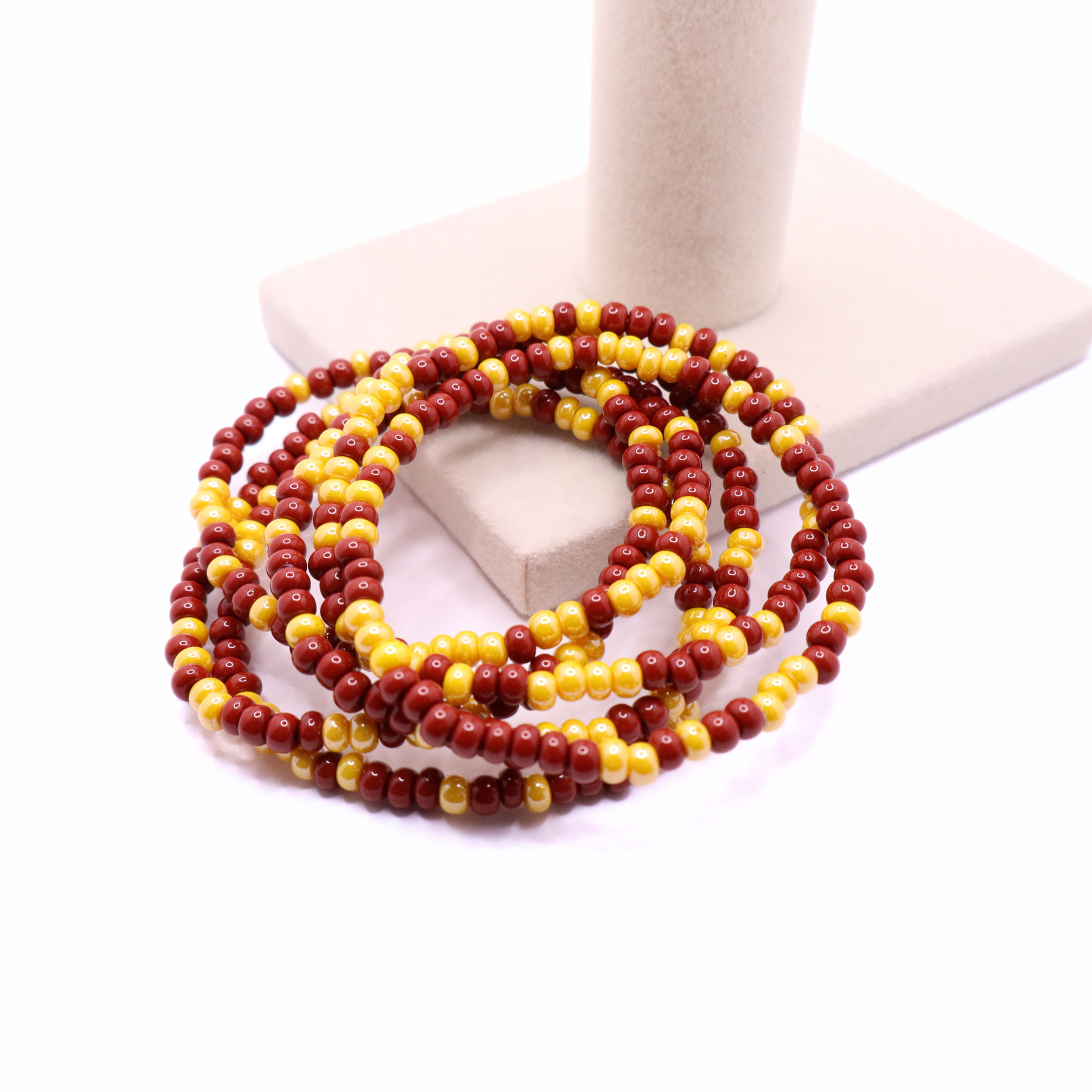 Set of six burgundy and gold seed bead stretch bracelets featuring random burgundy and gold seed beads on a white background