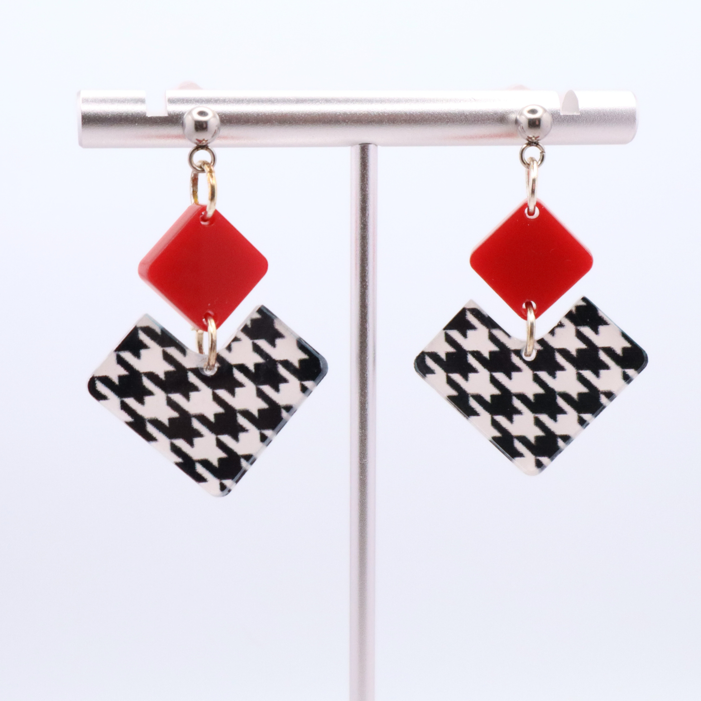 Pair of earrings with red and houndstooth pattern on a white background