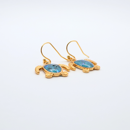 Gold turtle-shaped earrings with teal blue resin on a white background