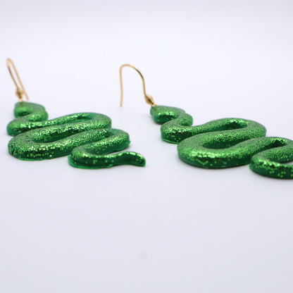 Green glittery snake-shaped earrings on a white background