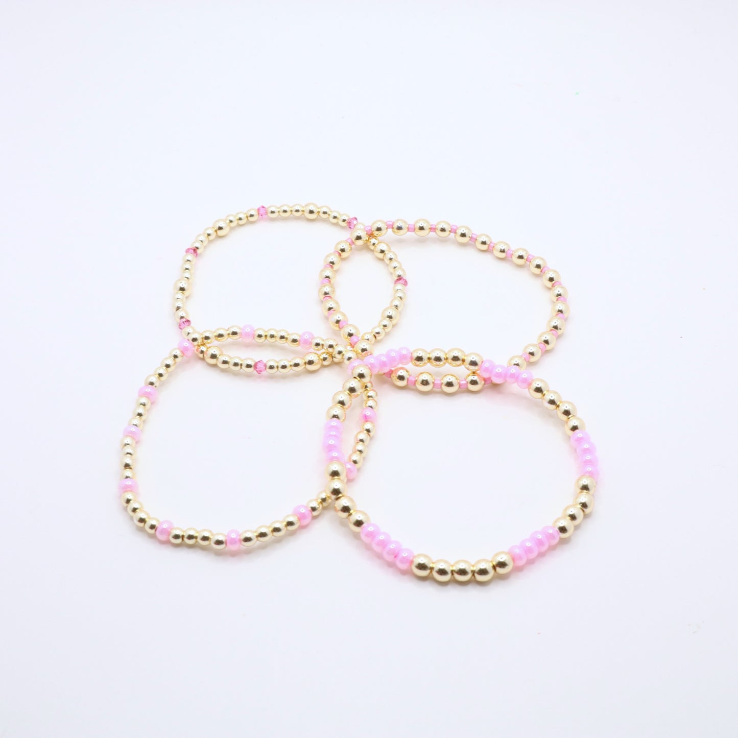 Pink and gold bracelet stack styled together for an elegant layered jewelry look.