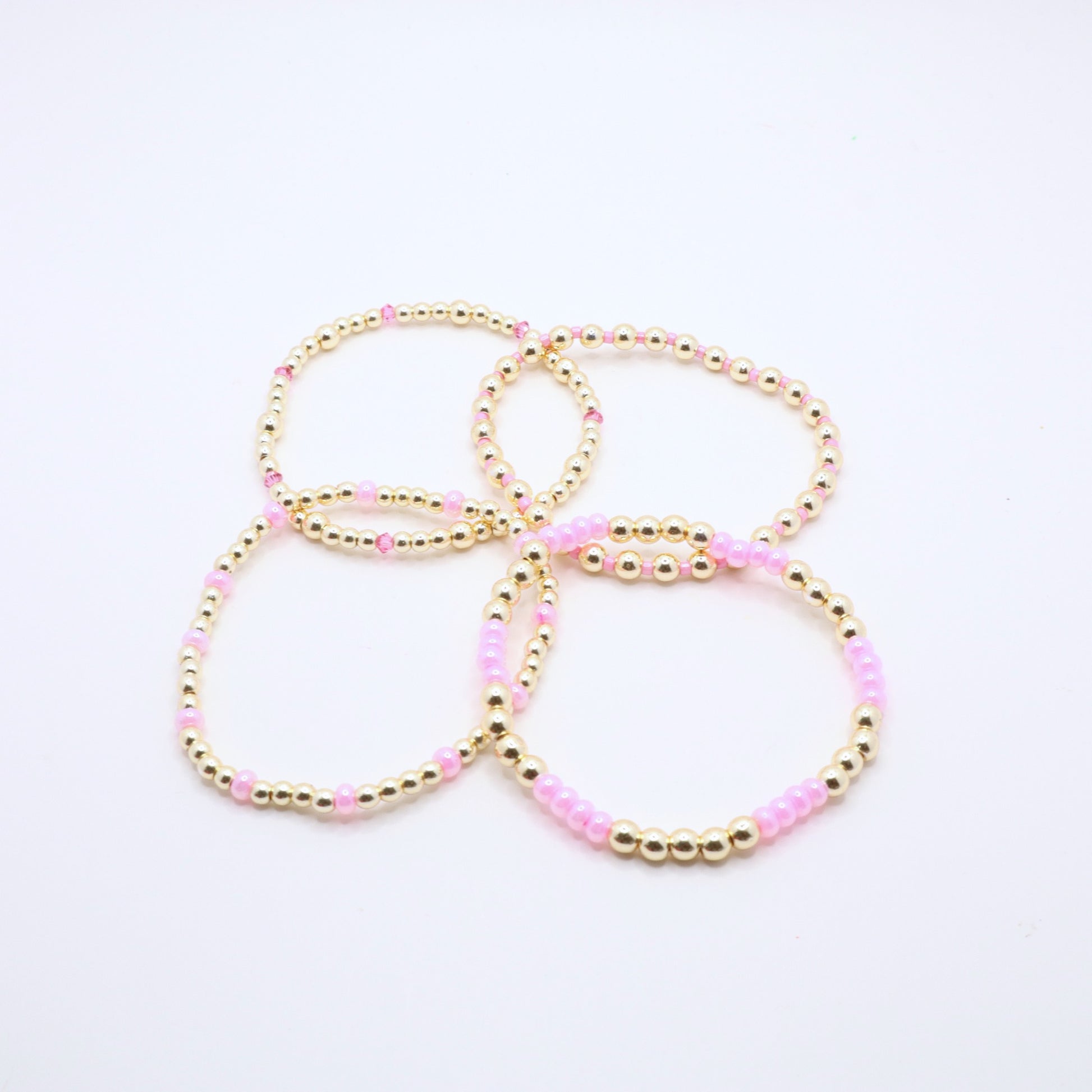 Pink and gold bracelet stack styled together for an elegant layered jewelry look.