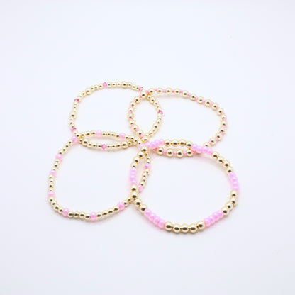 Pink and gold bracelet stack styled together for an elegant layered jewelry look.