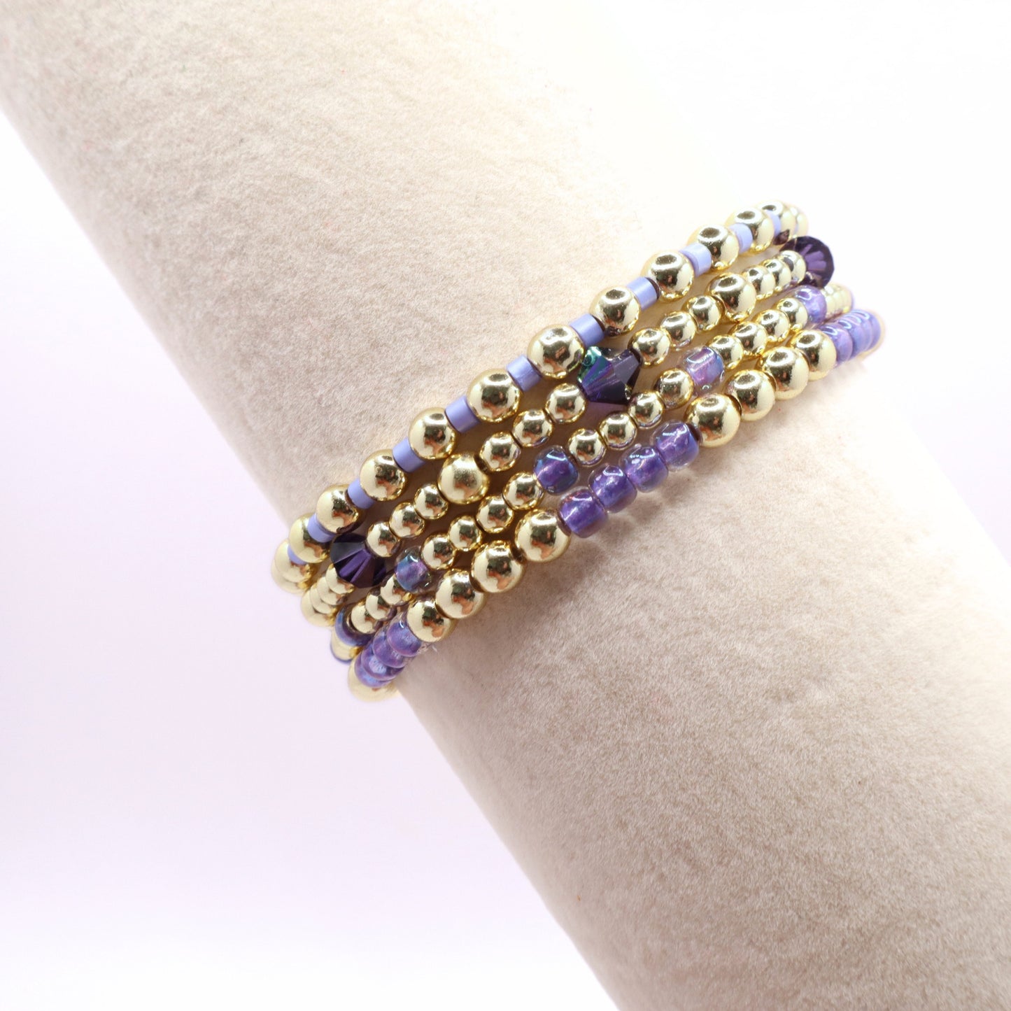 Five-piece lavender bead bracelet stack with gold accents and sparkling purple crystals.