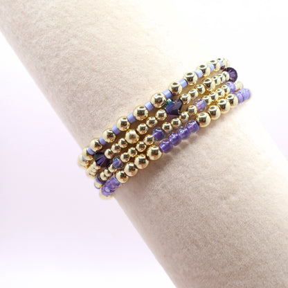 Five-piece lavender bead bracelet stack with gold accents and sparkling purple crystals.