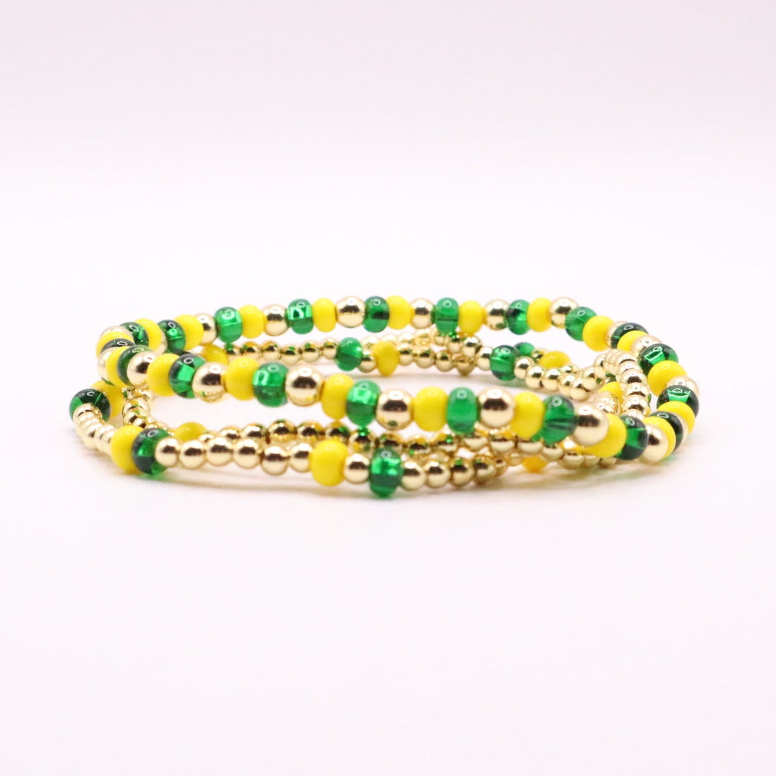 Set of green and yellow beaded bracelets on a white background