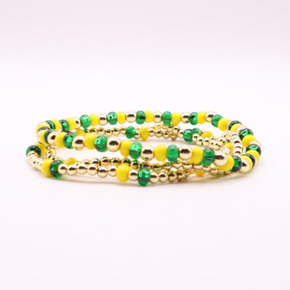 Set of green and yellow beaded bracelets on a white background