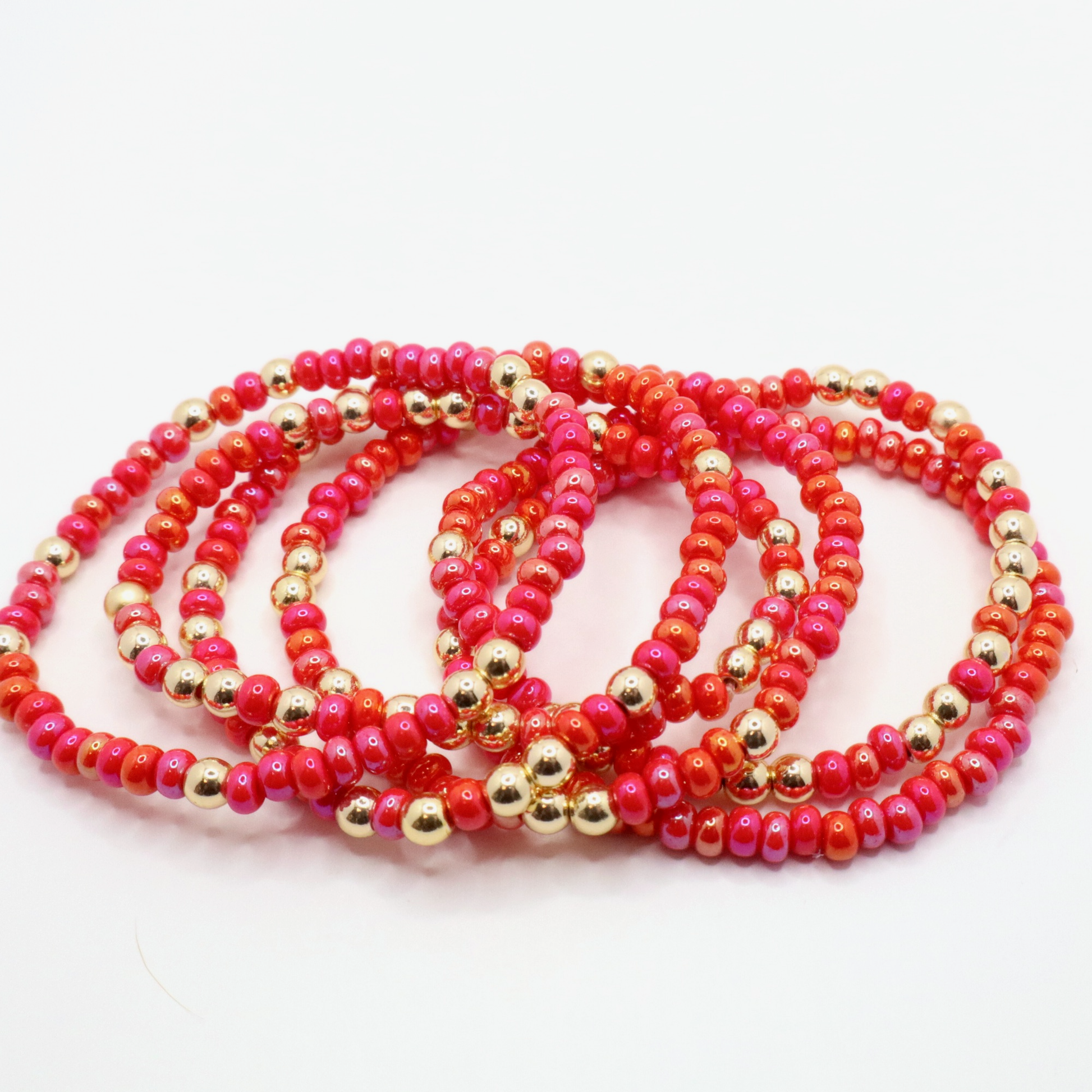 Set of six pink and gold beaded bracelets on a white background