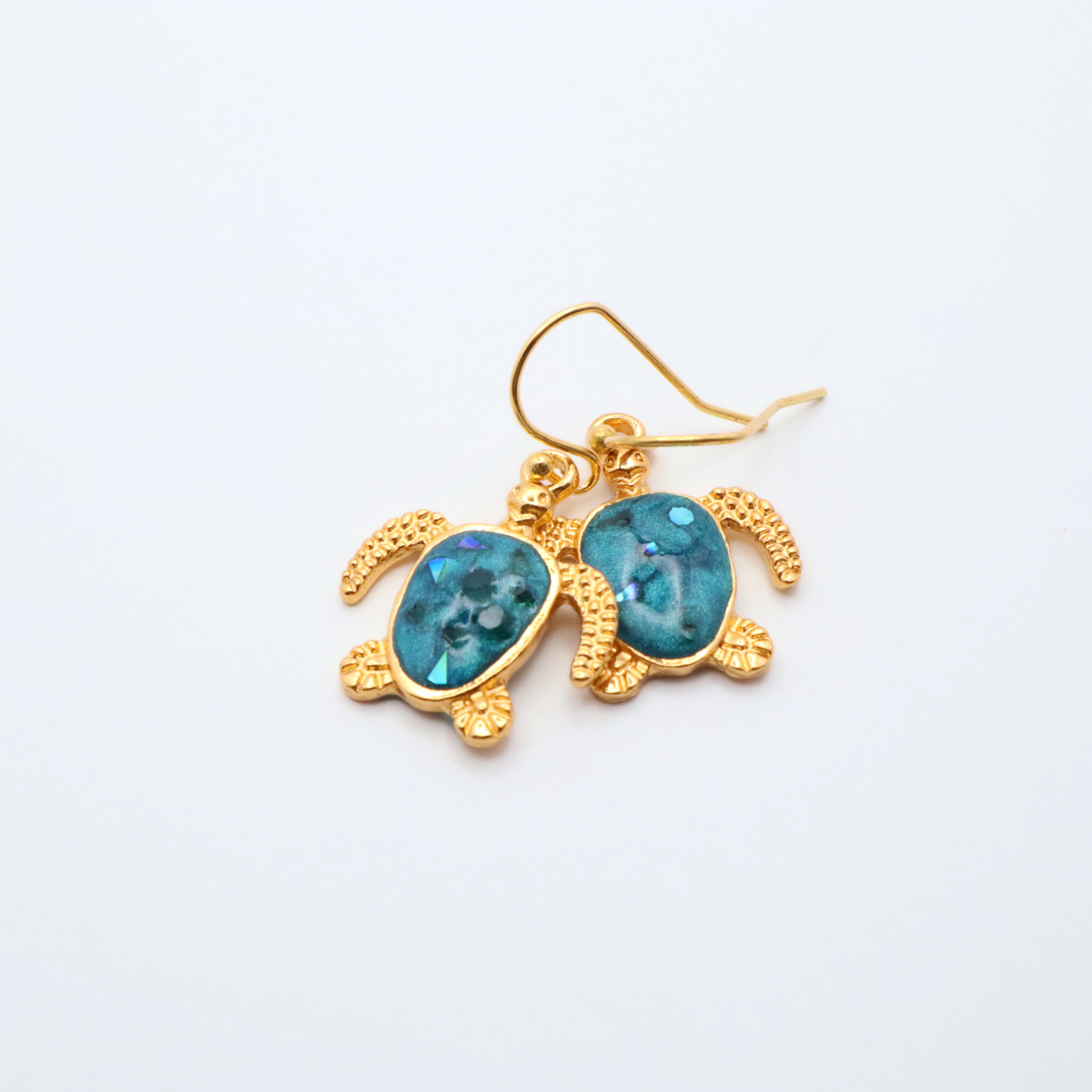 Gold turtle-shaped earrings with teal blue resin on a white background