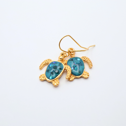 Gold turtle-shaped earrings with teal blue resin on a white background